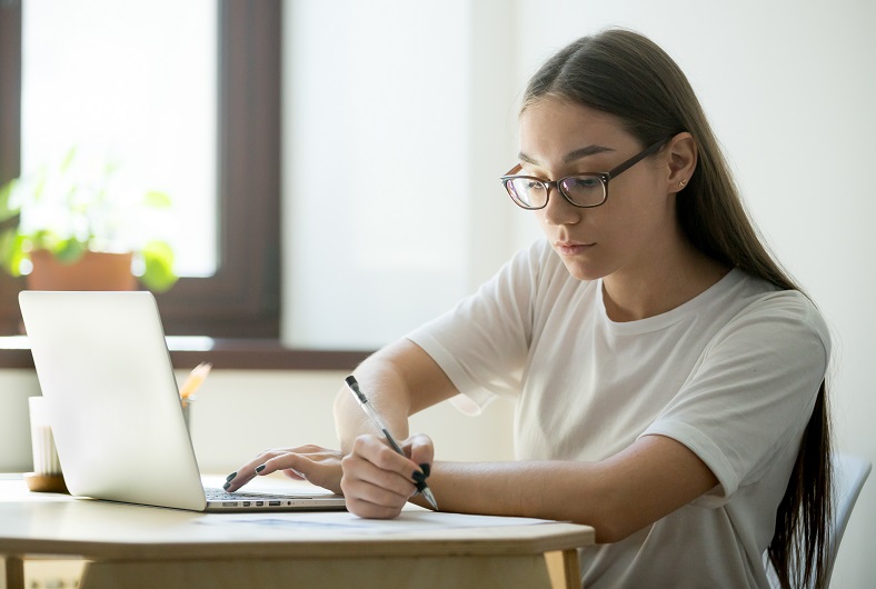 Studente die aan haar laptop een online examen aflegt