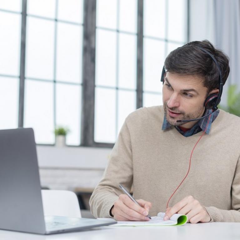  Un homme avec un casque qui suit une vidéoconférence sur son ordinateur portable