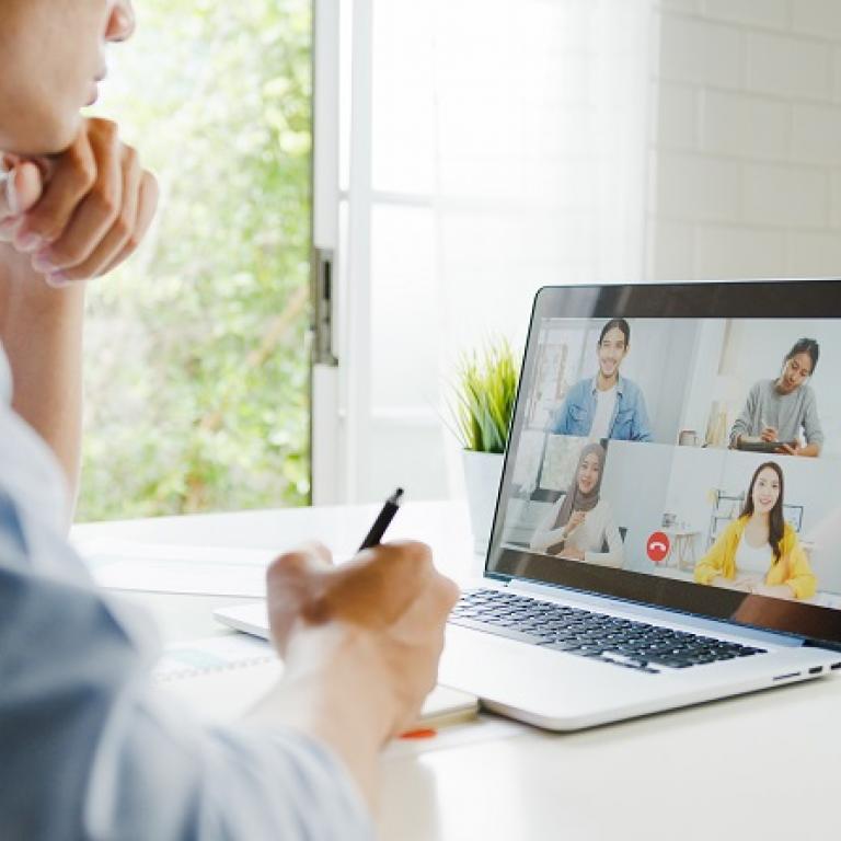 Man die met zijn laptop een videoconferentie volgt