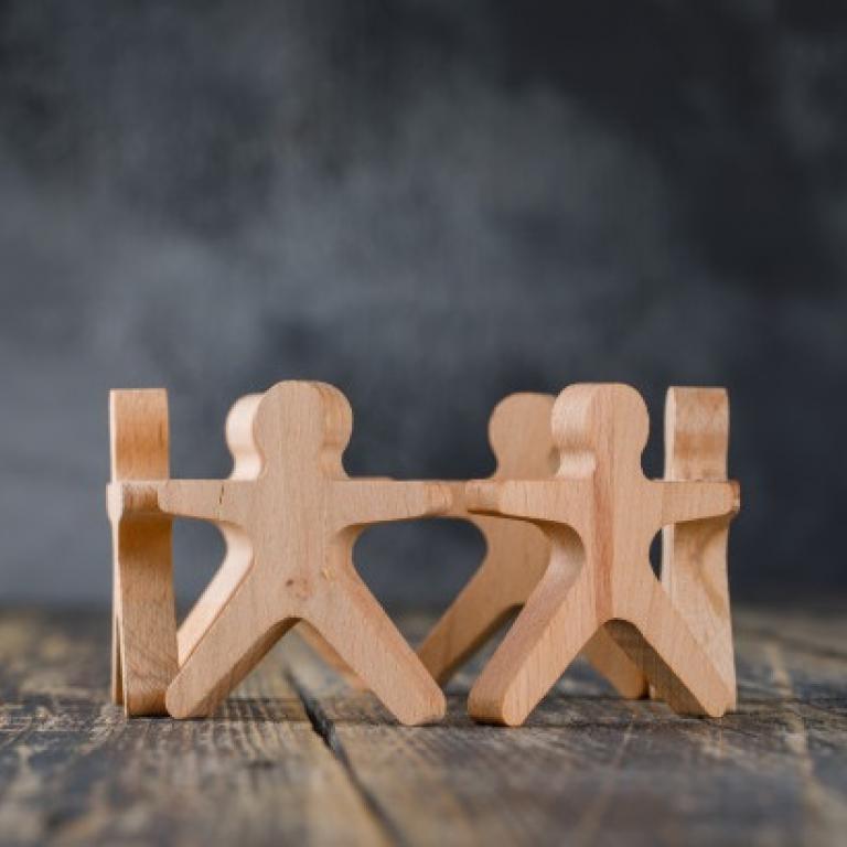 Concept van samenwerking uitgebeeld aan de hand van houten figuren in de vorm van mensen